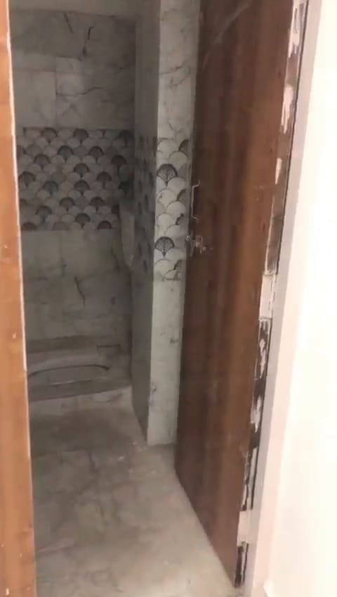 Bathroom with marble-look wall tiles, a patterned feature band and a wooden door frame.
